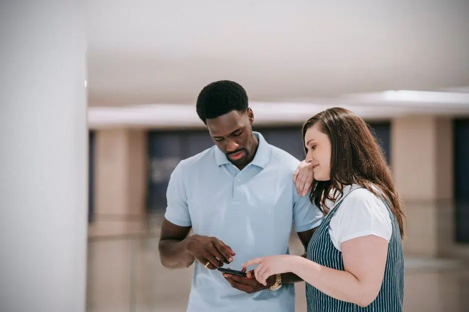 Un couple consulte son épargne sur smartphone devant une banque