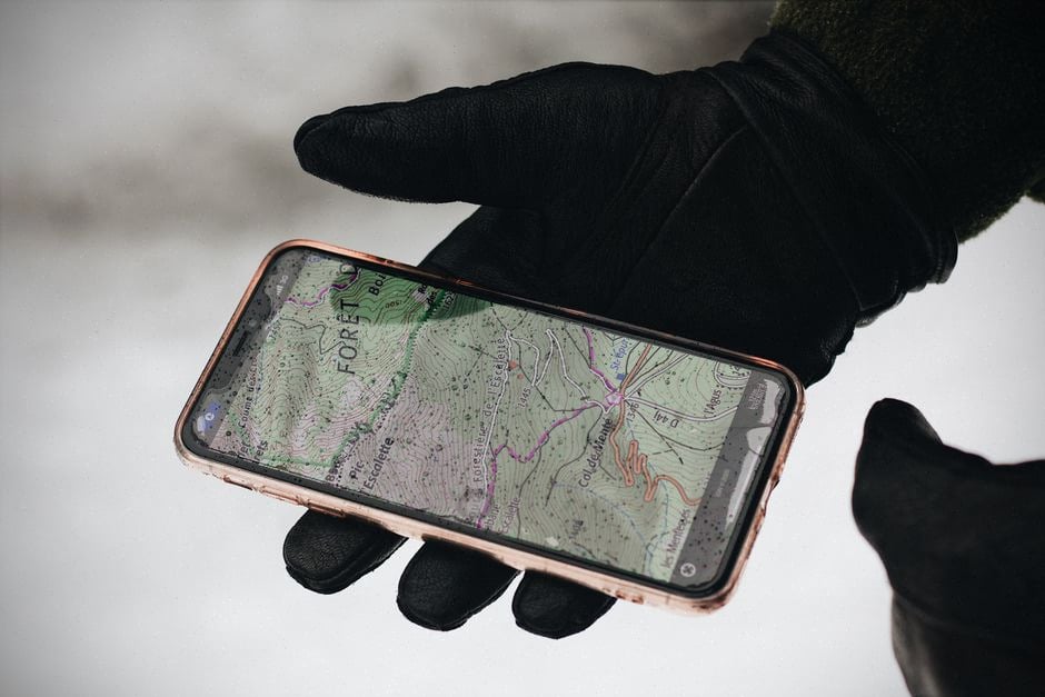 Carte topographique et smartphone utilisés pour préparer une randonnée sûre